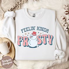 Feelin' Kinda Frosty Christmas Sweatshirt Funky Sassy Groovy Jumper Snowman Winter Cosy Sweater Ladies Christmas Gift for Her Womens Cute Welcome to ImayzeDesigns! ✨ Sleigh your seasonal style game with our sassy 'Feelin' Kinda Frosty' Christmas sweatshirt! This funky snowman design is sure to bring the perfect blend of cool and festive to your winter wardrobe ❄️💖☃️ THE SWEATSHIRT This classic Gildan 18000 unisex heavy blend crewneck sweatshirt is pure comfort! These garments are made from poly Cotton Tops With Funny Print For Winter, Funny Print Long Sleeve Winter Tops, Winter Long Sleeve Tops With Funny Print, Trendy Funny Print Tops For Winter, Cute Winter Letter Print T-shirt, Winter Crew Neck Top With Funny Print, White Sweatshirt With Funny Print For Winter, Winter Funny Print Crew Neck Top, Cute Winter Character Print Sweatshirt