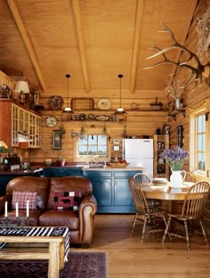 a living room filled with furniture next to a kitchen and dining room table covered in deer antlers