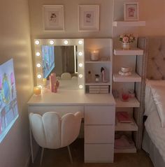 there is a vanity with lights on it and a mirror in the corner, next to a bed