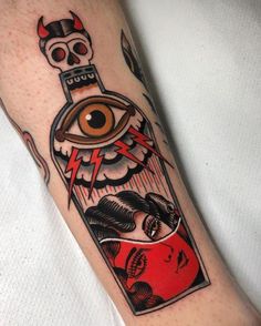 a bottle with an eye on it and a skull in the middle is sitting next to a person's leg