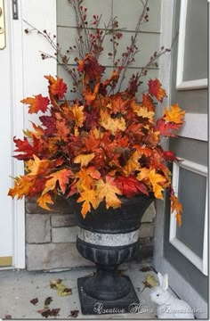 a planter filled with autumn leaves on the front porch