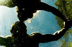 the silhouette of a man holding an umbrella under water