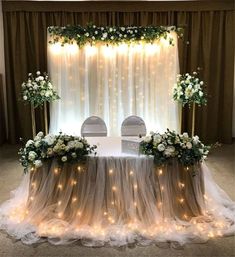 a table with white flowers and lights on it