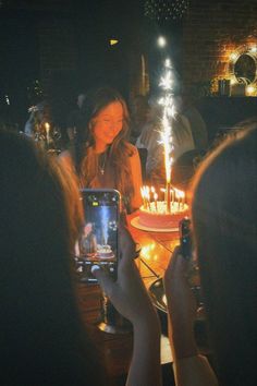 people taking pictures of a birthday cake with candles