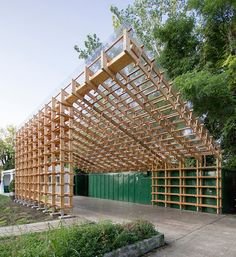 a large wooden structure sitting in the middle of a park with lots of greenery