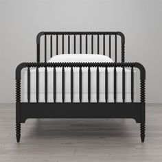 a black bed frame with white sheets and pillows on it, against a gray wall