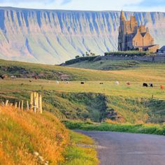 a large castle sitting on the side of a lush green hillside next to a road