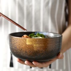 a person holding a bowl with chopsticks in it