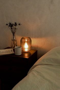 a lamp that is sitting on top of a table next to a book and vase