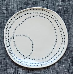 a white plate with black dots and lines on the edge is sitting on a blue cloth