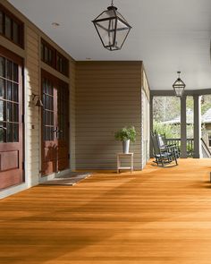 an empty porch with rocking chairs and potted plants