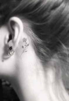 a woman's ear with a small flower tattoo on her left behind the ear