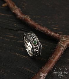 a silver ring sitting on top of a piece of wood next to a twig