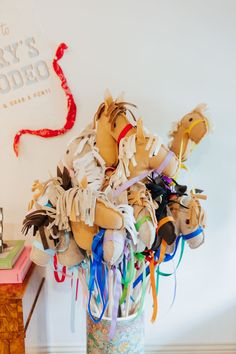 a vase filled with stuffed animals on top of a wooden table next to a wall