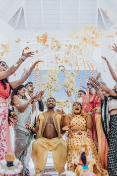 a group of people standing around each other with their arms in the air and throwing petals