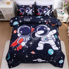 a bed with an astronaut themed comforter and pillow cases on top of the bed