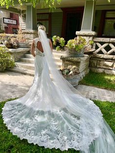 a woman in a wedding dress is standing on the grass with her back to the camera