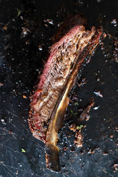 a piece of meat is sitting on a black surface with some brown stuff around it