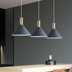 three pendant lights hanging over a dining room table