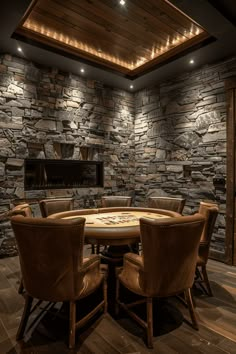 a round table with chairs around it in front of a stone wall and ceiling light