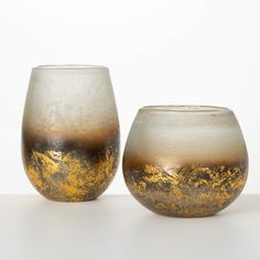 two glass vases sitting next to each other on a white counter top with gold flecking