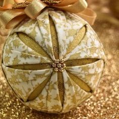 an ornament with a bow on top of it sitting on some gold glitter