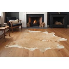 a living room with a fireplace, chair and cow hide rug on the wooden floor