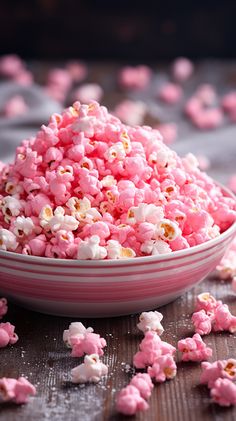 a bowl filled with pink popcorn on top of a wooden table next to other pieces of food