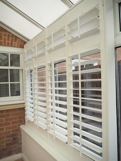 a window with white shutters in front of a brick wall