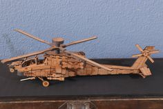 a wooden model of a helicopter sitting on top of a table next to a blue wall