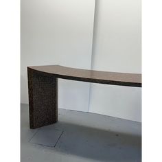 a wooden bench sitting in front of a white wall with a black and brown design on it