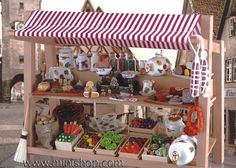 a wooden stand with lots of food on it's sides and a striped awning over the top