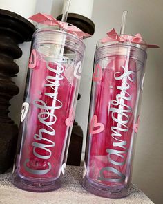 two pink tumblers with the words love and hearts on them sitting next to each other