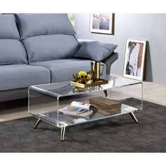 a glass coffee table sitting on top of a rug in front of a blue couch