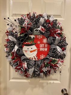 a christmas wreath on the front door decorated with black, white and red ribbon decorations