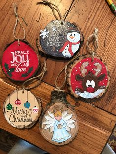 four christmas ornaments are hanging on a wooden table