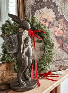 a christmas wreath on top of a mantle with a rabbit figurine next to it