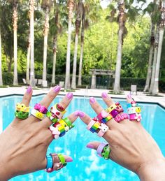 someone is holding up their nails in front of a swimming pool with palm trees behind them