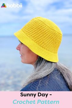 a woman with grey hair wearing a yellow knitted hat by the water's edge