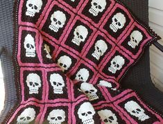 a crocheted blanket with skulls on it is sitting in front of a chair