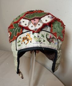 This antique 19th century Chinese festival hat is a stunning piece that showcases exquisite embroidery on silk and fabric. The hat features embroidered animals on the forehead with intricate detailing, from the region of China, and very well made.  It features a stylized design with two ear covers on the sides. The hat is a beautiful addition to any collection of Asian antiques and embroideries. This piece of history is perfect for anyone looking to own a unique and elegant item that speaks to the rich culture of China. It is in good antique condition with normal ware. Vintage Embroidered Festival Hat, Chinese Hat Traditional, Traditional Chinese Headpiece, Chinese Opera Headdress, Chinese Hat, Chinese Festival, Festival Hat, Asian Antiques, Costume Hats