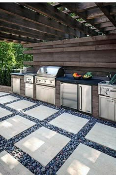 an outdoor kitchen with stainless steel appliances and stone flooring