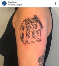 a woman's arm with a small house tattoo on it