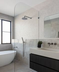 a white bath tub sitting next to a bathroom sink under a large mirror and a window