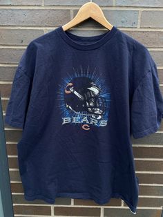 "Vintage 1990s Chicago Bears NFL Graphic T-Shirt - Size XL (Length 28.5\", Chest 23\") - Overall great vintage condition (no holes/no stains) - Message me for more information Please take note of the measurements listed as these are vintage clothes and may fit different than the tag size. Follow our page for more vintage clothing drops! Connect with us on Instagram: @recurarchives" 90s Style Logo Print Tops For Fans, 90s Style Tops With Logo Print For Fans, 90s Logo Print Tops For Fans, 90s Style Logo Print Fan Merchandise Tops, Throwback Graphic Print Short Sleeve Tops, Throwback Style Short Sleeve Graphic Print Tops, Throwback Style Short Sleeve Tops With Graphic Print, 90s Logo Print Tops For Fan Merchandise, 90s Graphic Print Tops For Fan Gear