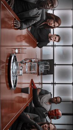 three people standing in front of a wooden table