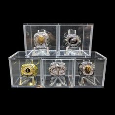 four different types of rings are in a clear display case on a black background and one is gold, the other is silver