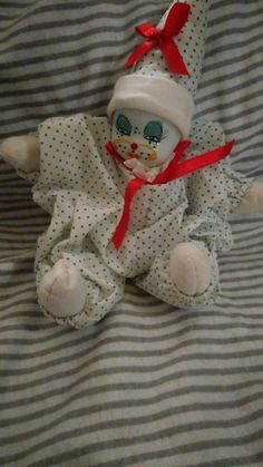 a small stuffed animal wearing a white and red hat on top of a striped blanket