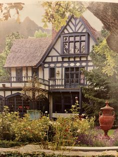 an old photo of a house in the middle of some trees and bushes with flowers around it