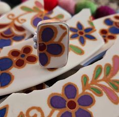 a close up of a ring on top of some plates with flowers and leaves painted on them